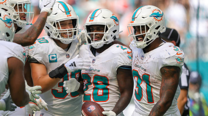 Dolphins running back De'Von Achane, center, celebrates his touchdown with fellow tailback Raheem Mostert, right, and fullback Alec Ingold, left, against the Denver Broncos.